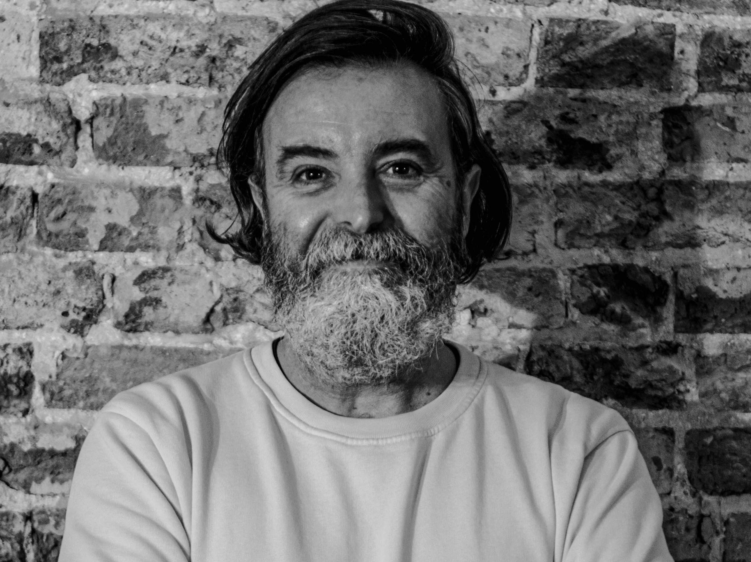 Black and white portrait of chef, Nuno Mendes in front of a brick wall