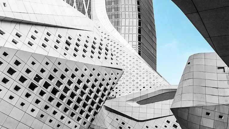 Futuristic curved white buildings with lots of windows against a bright blue sky.