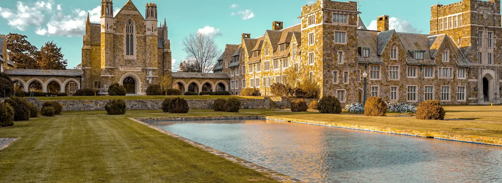 Landscape view of garden and square pool outside of rustic grand building