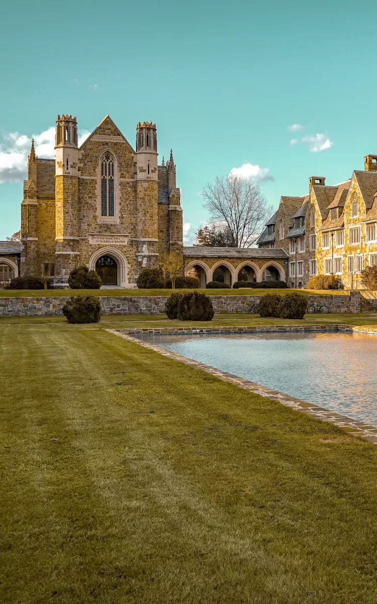 Landscape view of garden and square pool outside of rustic grand building