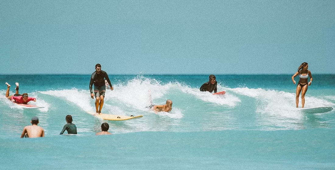 Group of people swimming and surfing in blue sea waves