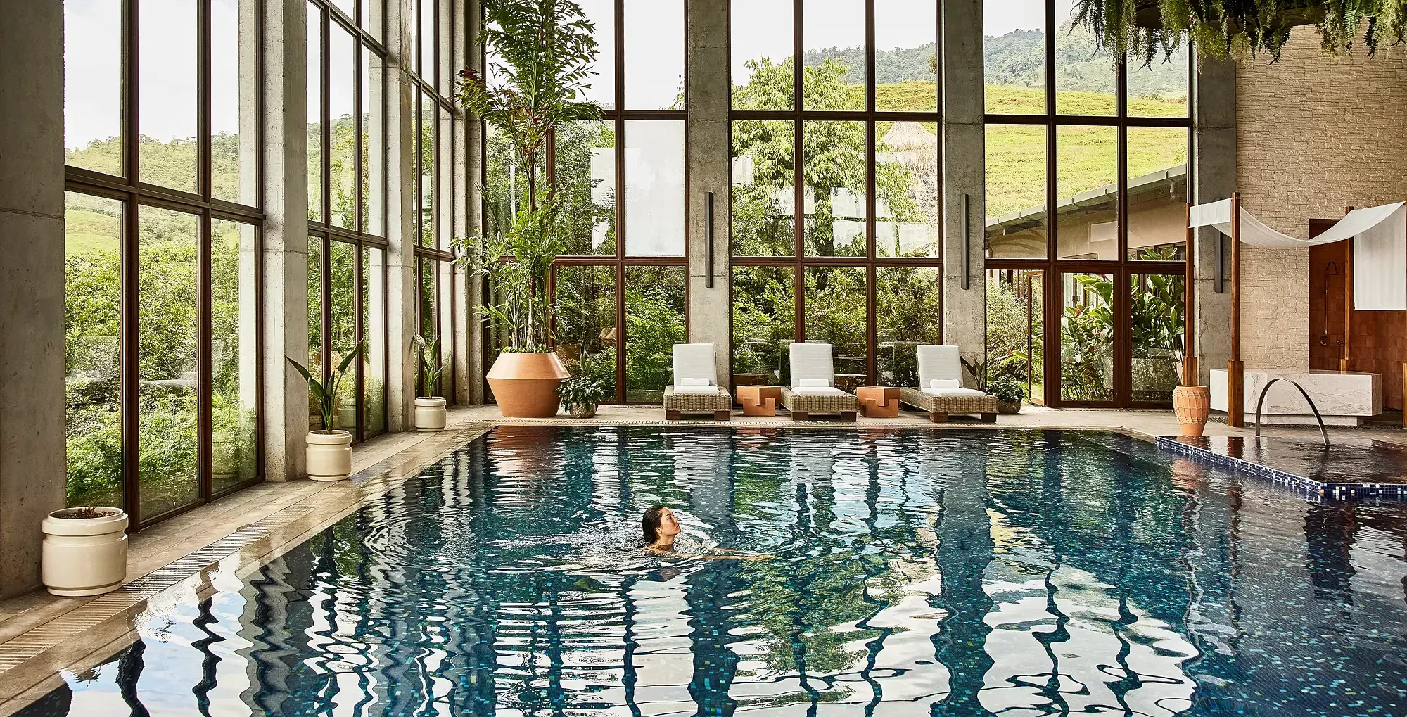 Women swimming in in-door luxury spa pool with big glass windows looking out to the landscape