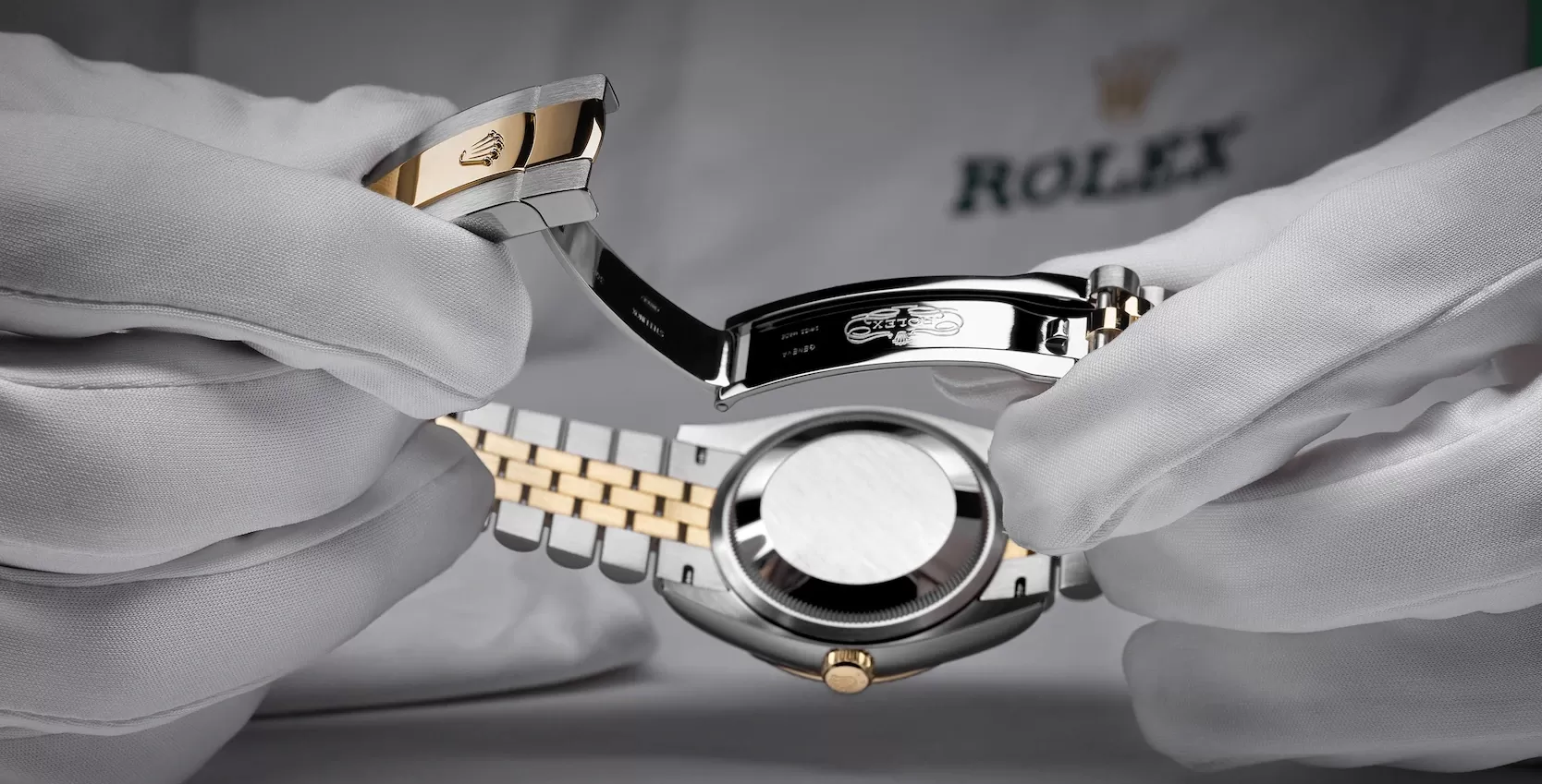 Rolex staff wearing uniform and gloves holding a luxury silver and gold Rolex watch