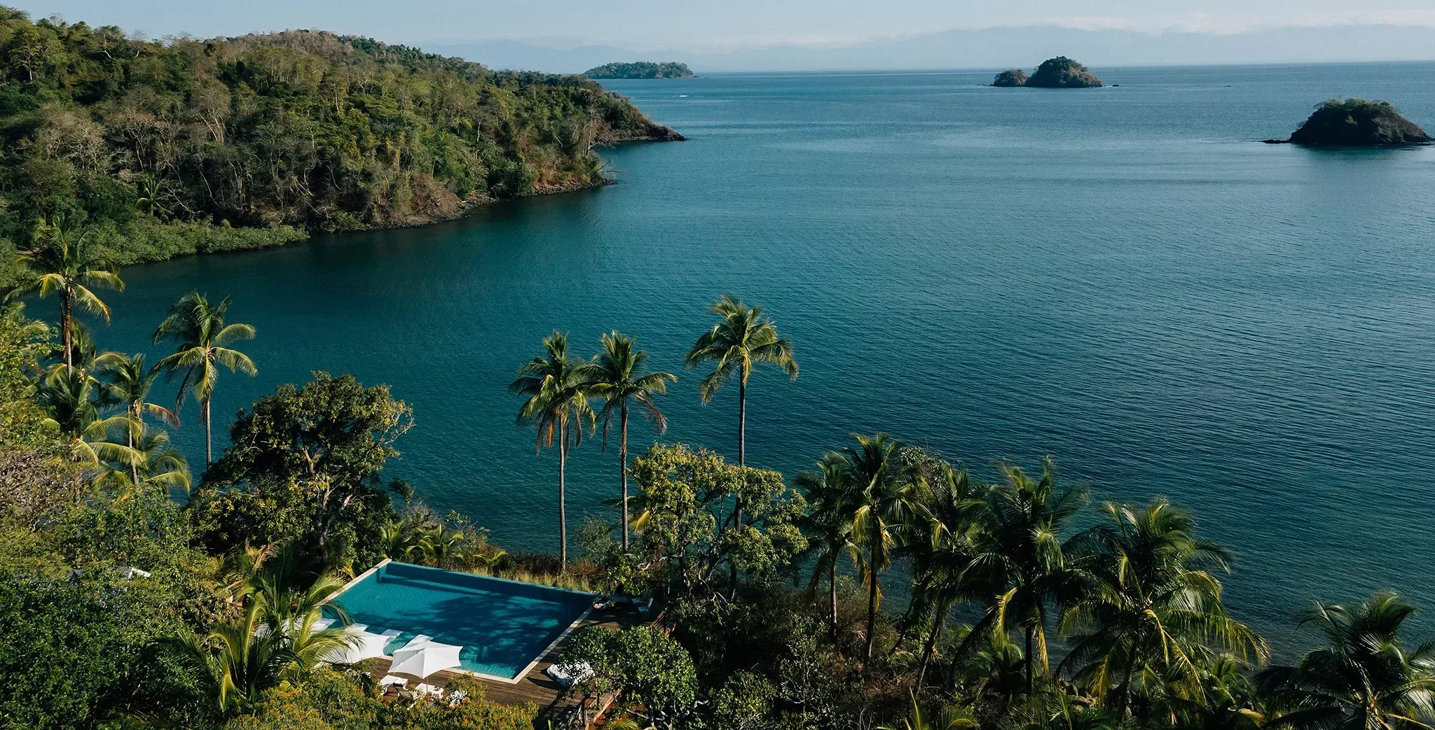 Pool on a cliff in between forest overlooking the ocean
