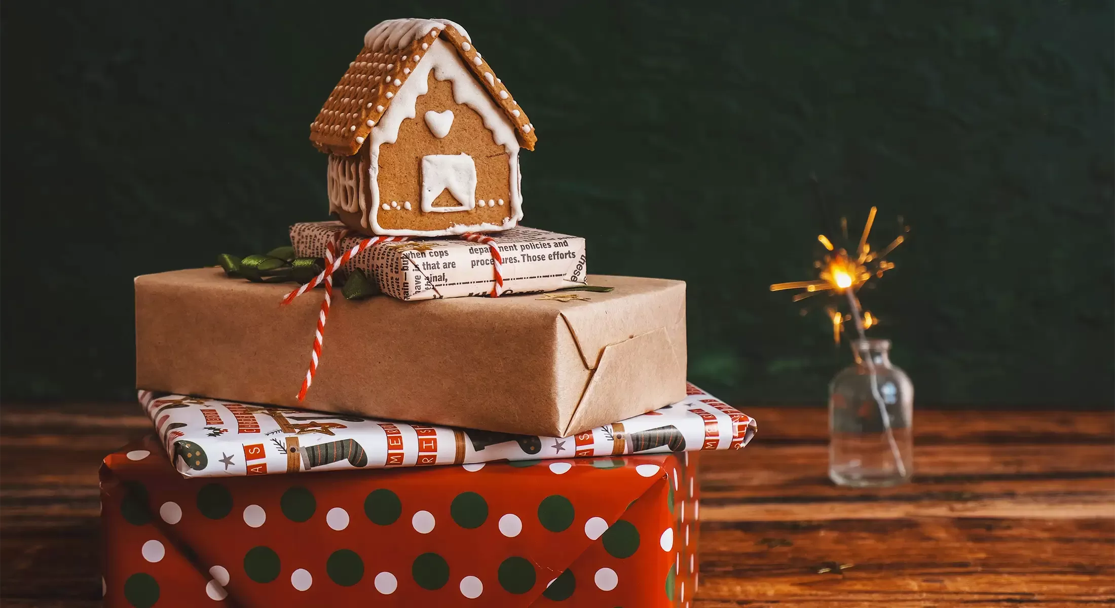 Christmas presents wrapped neatly in a pile with a ginger bread house on top.