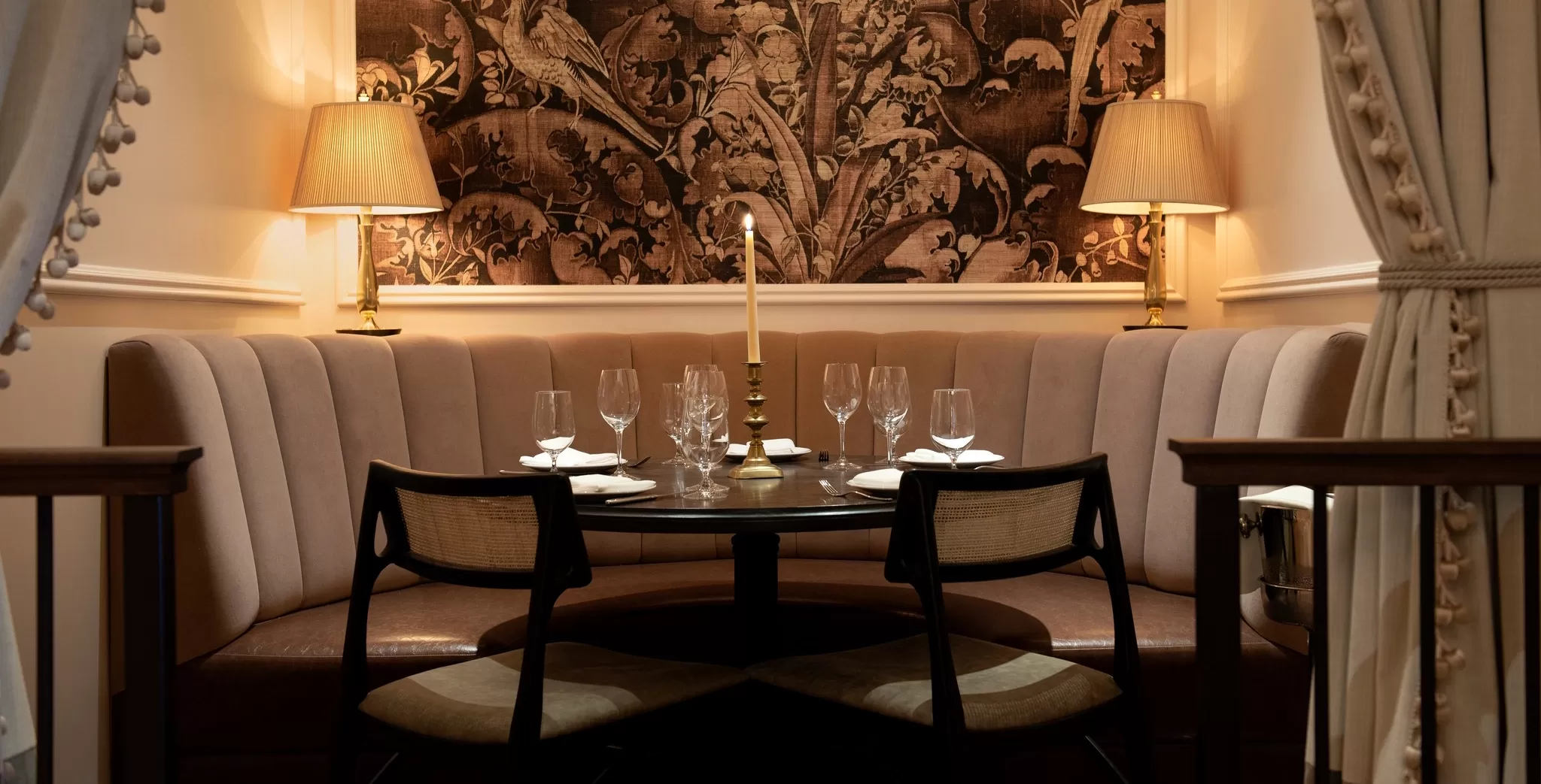Private dining booth with pink pleated sofa and printed wallpaper at La Marchande, New York