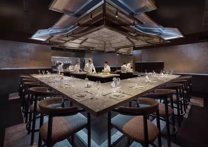 A spacious Dosa restaurant featuring a long table surrounded by chairs, inviting guests for a communal dining experience.