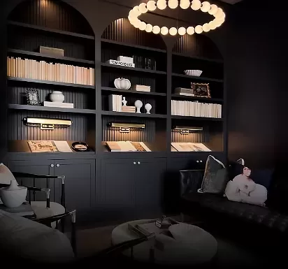 A dimly lit, elegant library room with black bookshelves filled with books and decorative items. A unique overhead chandelier with globe lights illuminates the space. The room features a black sofa, armchairs, and a round coffee table.