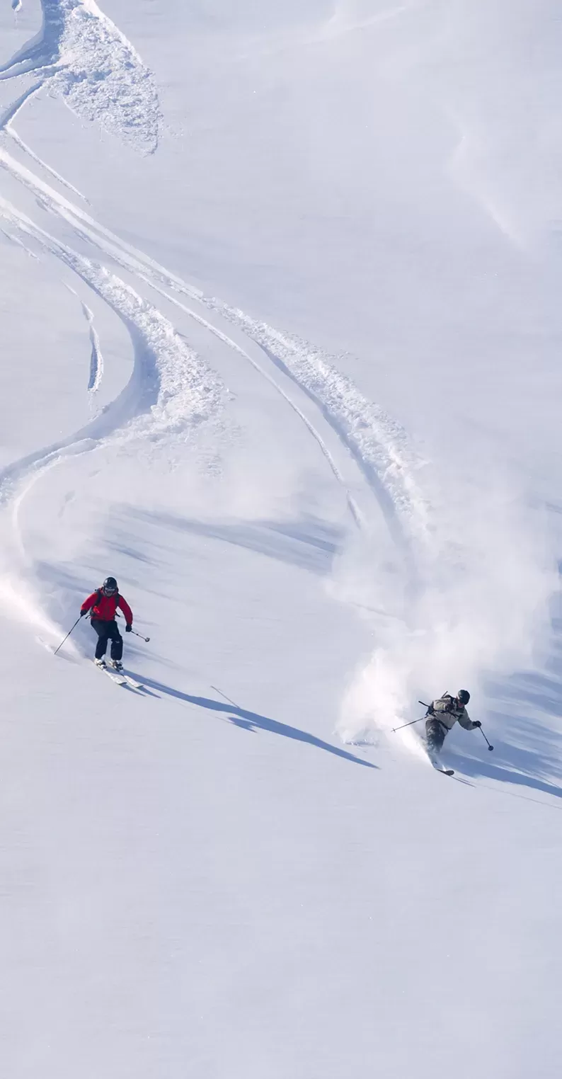 Three people skiing down slopes in the Alpes, France