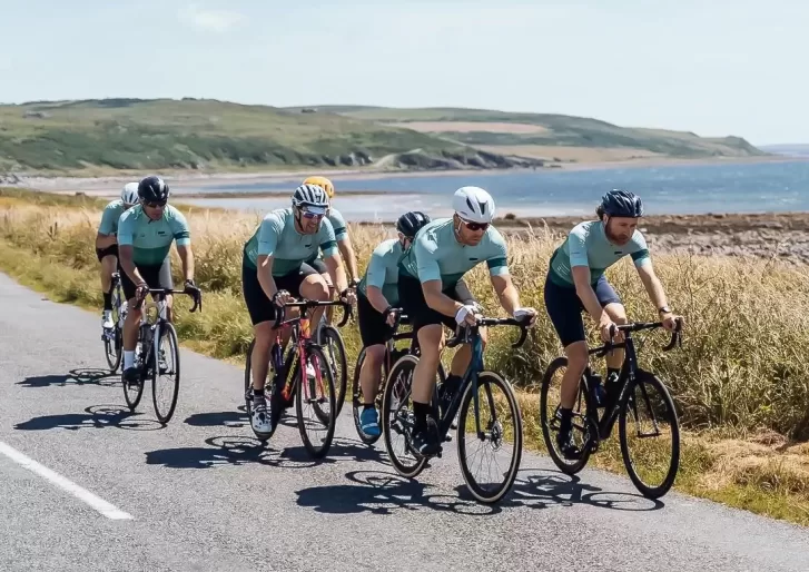 Group of cyclists cycling on road next landscape and sea view on 'led by leaders' cycling exhibition by Le Blanq in Norway