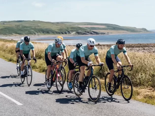 Group of cyclists cycling on road next landscape and sea view on 'led by leaders' cycling exhibition by Le Blanq in Norway