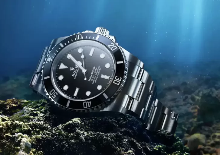 Rolex Submariner watch: Oystersteel - M124060-0001 sat in the bottom of sea on rocks